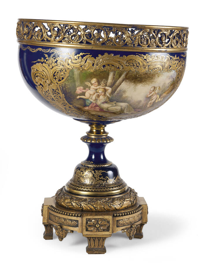 ALZATA - Grande alzata in porcellana di Sevres montata in bronzo dorato, fine XIX secolo, con due dipinti raffiguranti una scena di paesaggio e una scena con putti