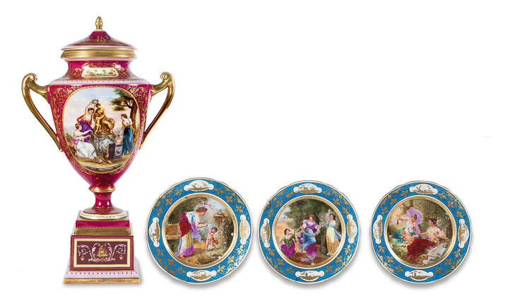 QUATTRO OGGETTI - Lotto composto da quattro oggetti: un vaso in porcellana con coperchio e manici, Vienna fine XIX sec., a fondo rosso dorato e con tre dipinti con scene del mondo antico; tre piatti in porcellana di Vienna XX sec. decorati a spolverino a scene con amorini. Difetti  