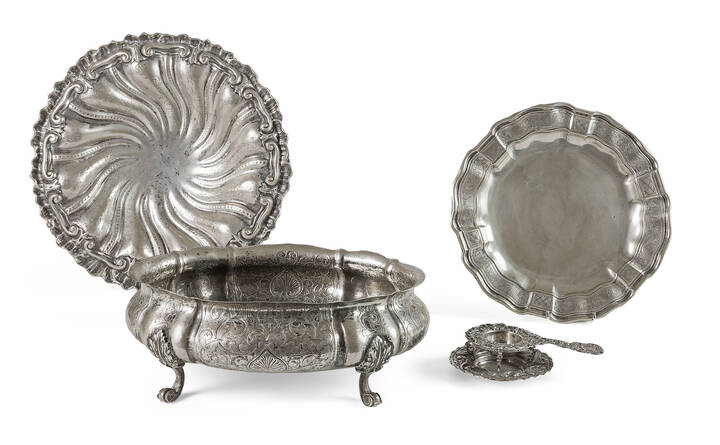 LOTTO DI QUATTRO OGGETTI IN ARGENTO - Lotto composto da quattro oggetti in argento, fine XIX inizio XX secolo: due centrotavola con piedini, uno di forma ovale cesellato e battuto con decori vegetali; un piatto con bordo mosso cesellato a motivi vegetali; un colino per il the con base