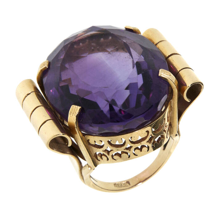 ANELLO - Anello in oro giallo con grande ametista centrale taglio ovale, trattenuta da due volute laterali 