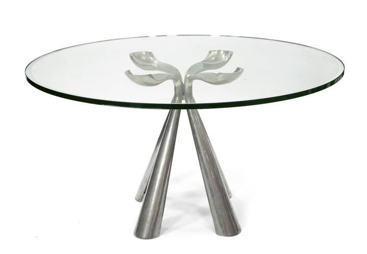 VITTORIO INTROINI - Colby<br>Tavolo in acciaio personal pressofuso, piano in cristallo con fascia perimetrale specchiata.
